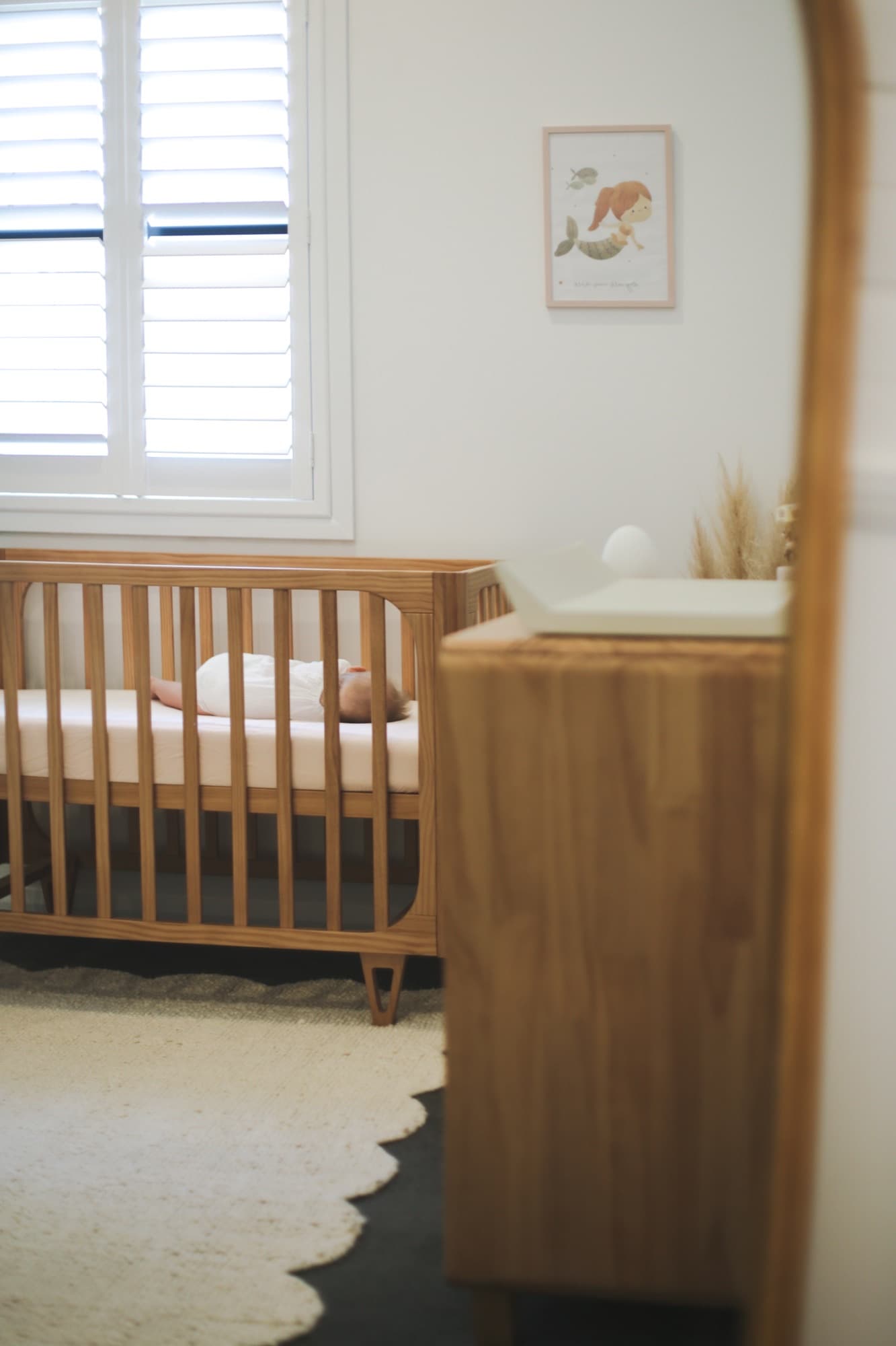 A calm nursery with a baby sleeping in a wooden crib